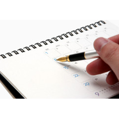 手拿钢笔在台历上记事